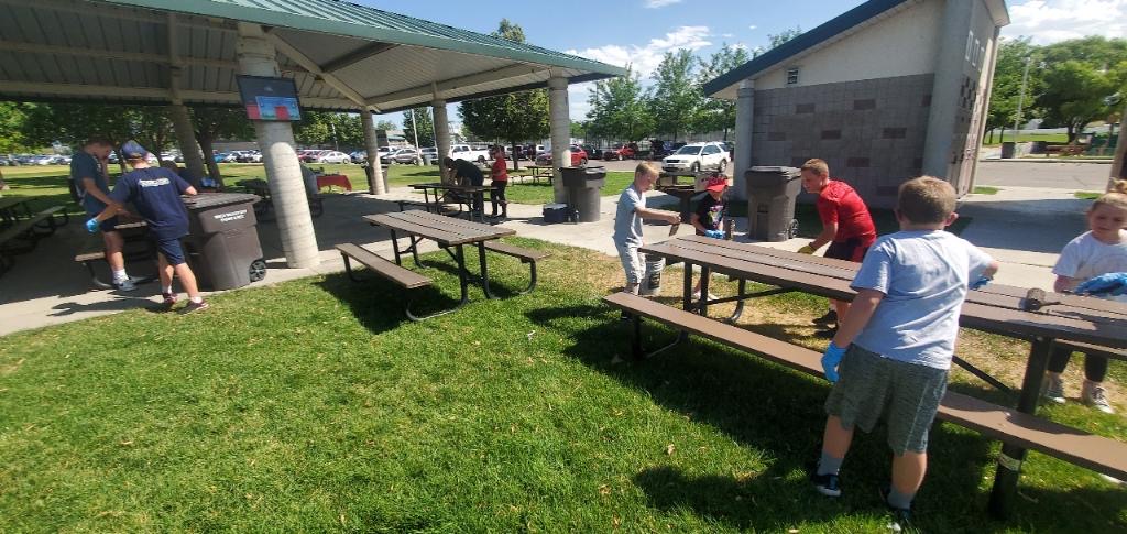 Volunteers cleaning picnic tables at a park pavilion