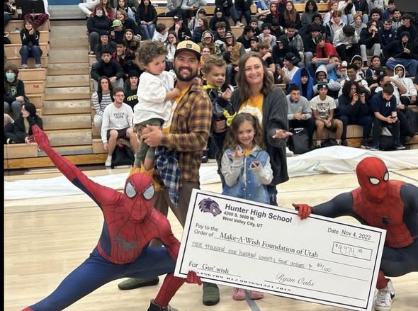 Family and Spider-Man characters beside a Hunter High School Make-A-Wish check